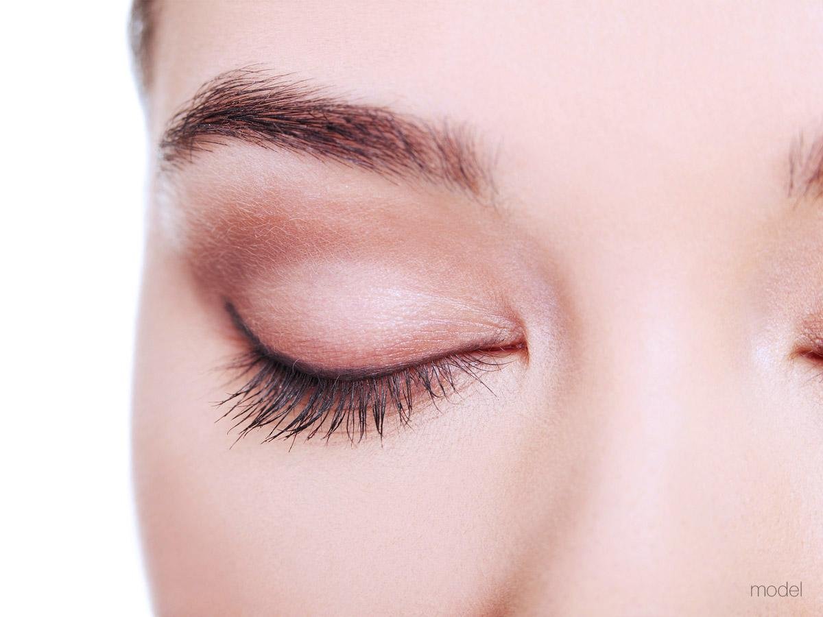 Close-up of a full, dark, well-shaped eyebrow above a model's closed eye