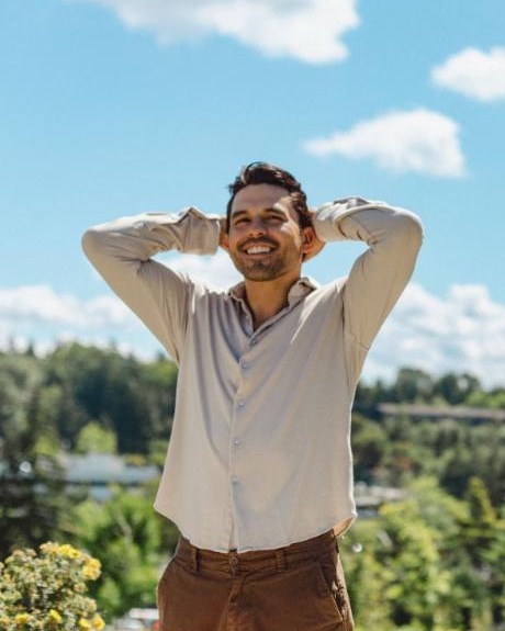 A smiling man with a full head of hair outdoors